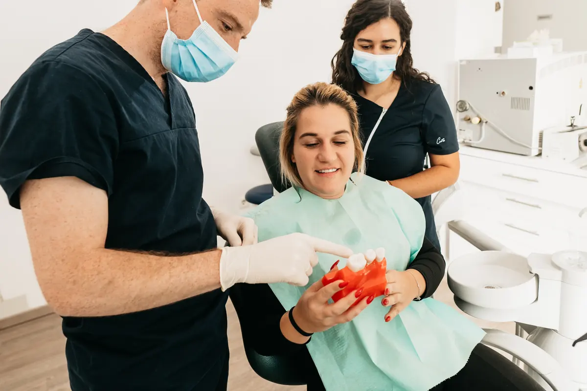 Stomatolog pacijentici na modelu objašnjava ugradnju zubnog implantata